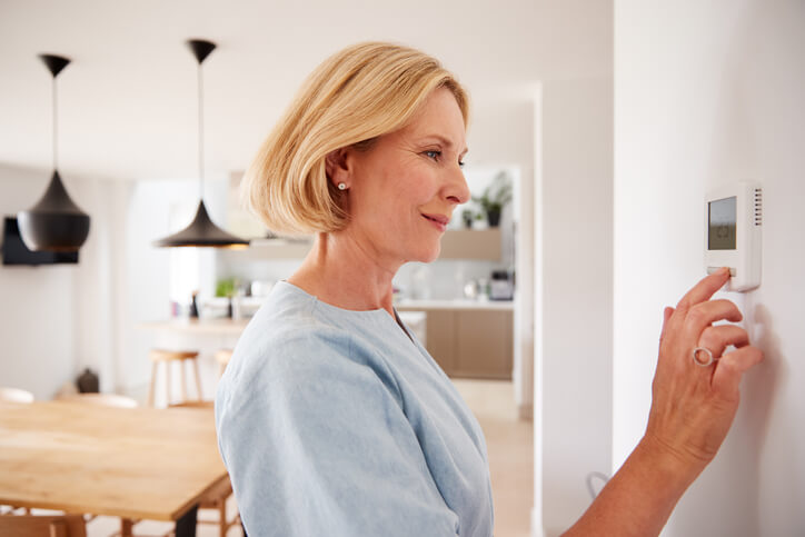 Woman Setting Up The Thermostat